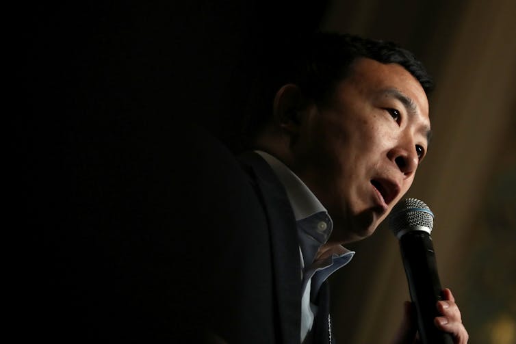 A picture of Andrew Yang speaking into a microphone.