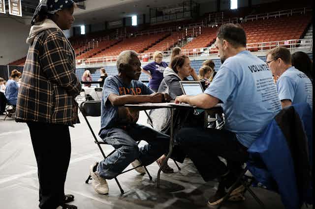 a health-care volunteer provdies services to a resident at a health camp in an indoor arena.