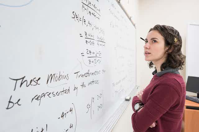 a female college student looks at equations on a whiteboard