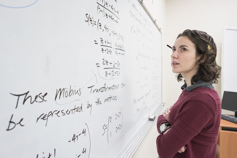a female college student looks at equations on a whiteboard