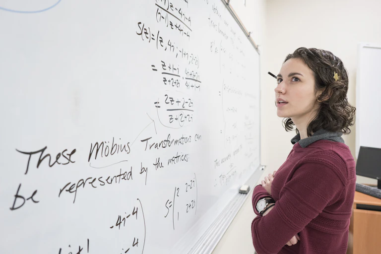 a female college student looks at equations on a whiteboard