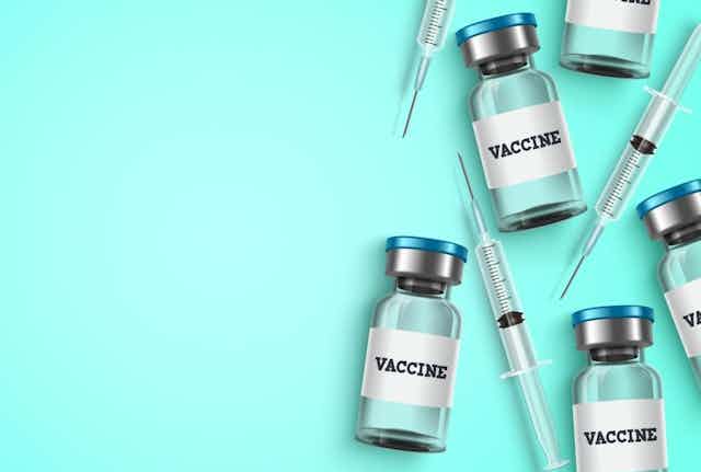 Illustration of vaccine bottles and syringes laid flat on a blue surface