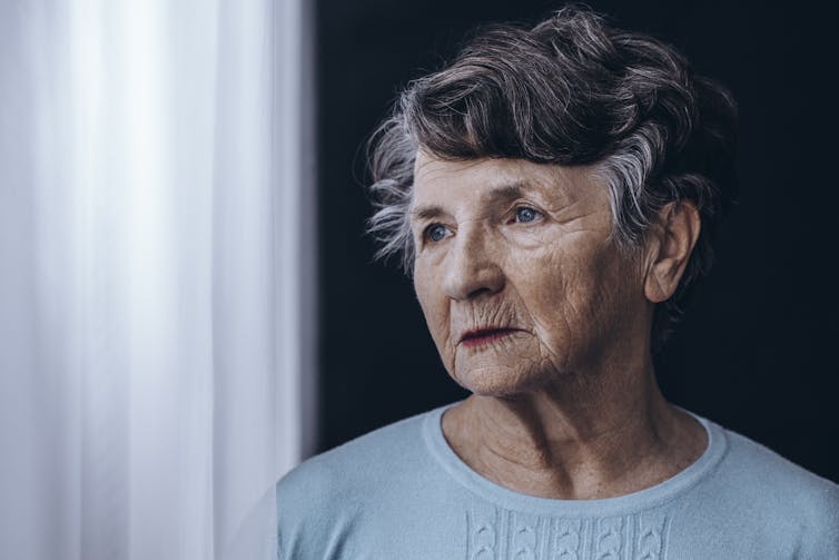 Elderly woman looking out a window.