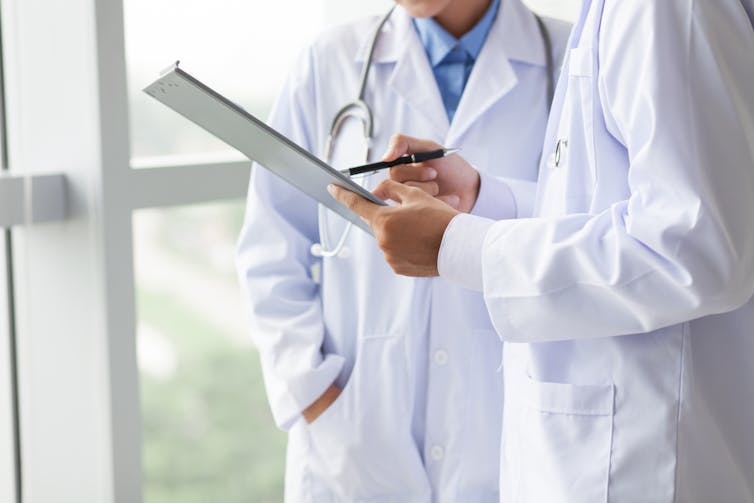 Two doctors looking at clipboard.