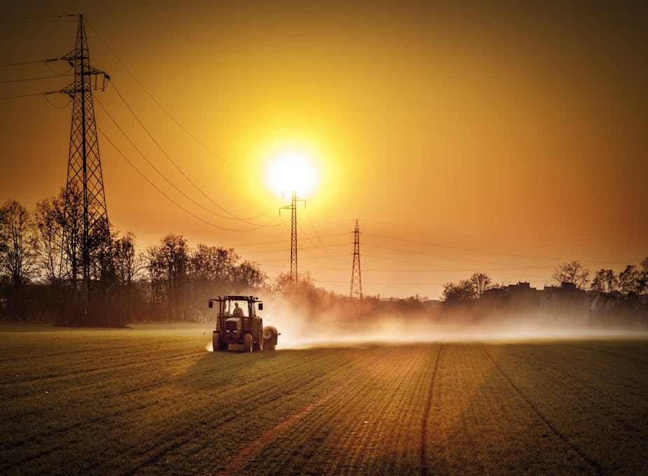 A tractor on a dusty field at sunset.