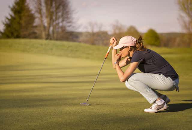 Golfer crouching down and concentrating on next putt.