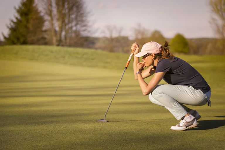 Golfer crouching down and concentrating on next putt.