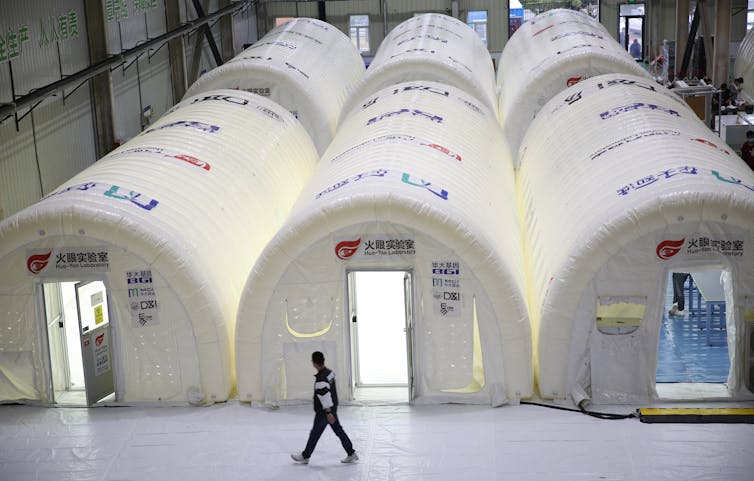 A man walks past three inflatable pop-up labs.