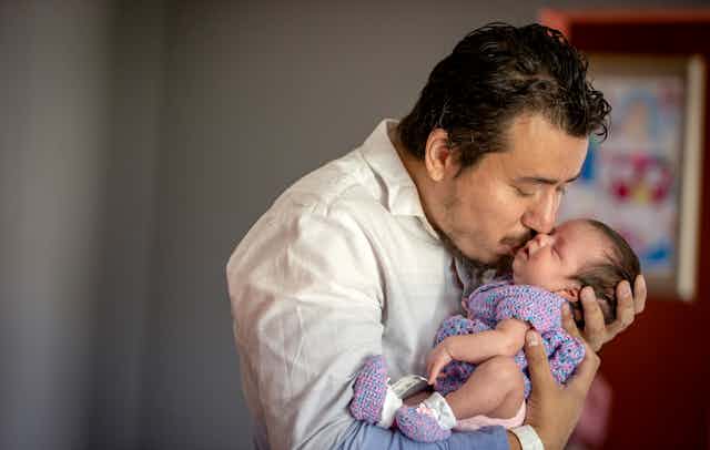 A man kissing his newborn daughter.