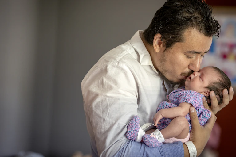 A man kissing his newborn daughter.