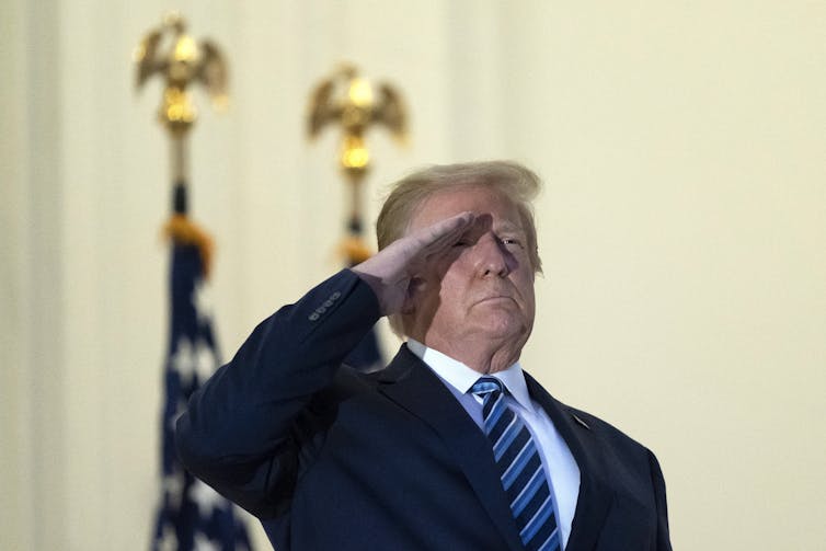 Trump salutes on a White House balcony.