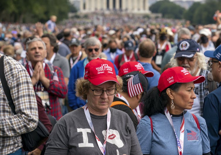 People wearing hats saying 'Let's make America godly again.'