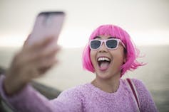 Mujer joven con cabello rosado tomando un selfie