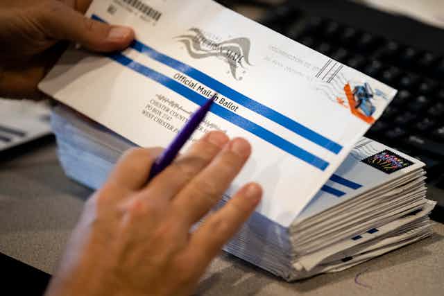 A person handles a mailed ballot