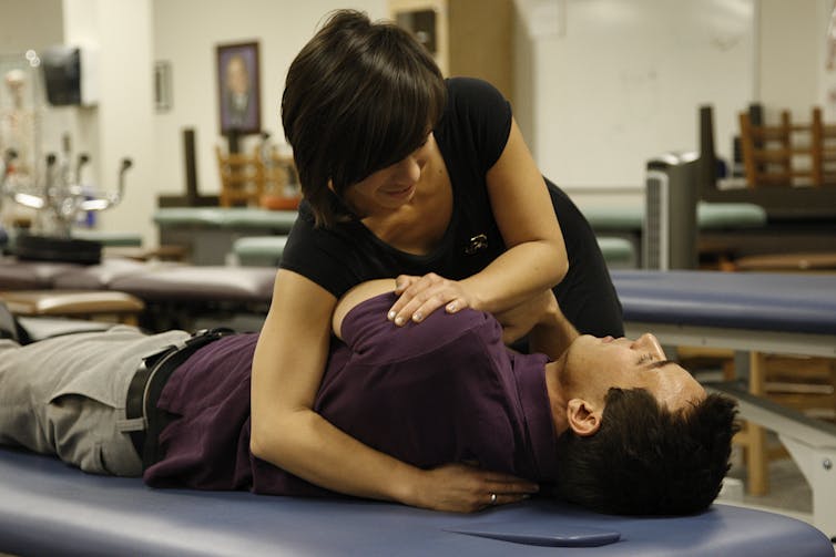 woman manipulating a man lying on a treatment table