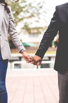 Image of a woman and a man holding hands, cropped to focus on their linked hands.