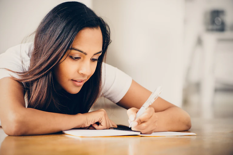A teenage girl writing in notebook