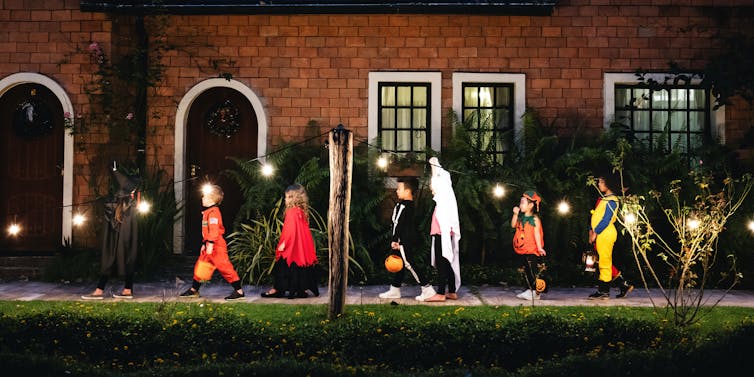 Young children dressed on Halloween costumes gong from door to door in search of treats
