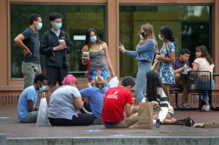 A dozen students sit outside at Tufts University