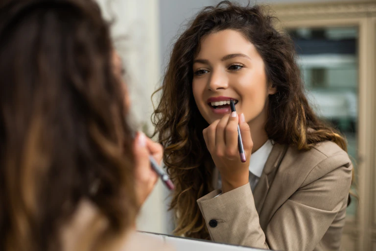 Office woman applying lipstick at mirror