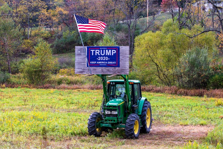 Un panneau de réélection Trump 2020 et un drapeau américain sont affichés dans une pièce d’équipement agricole à Valley Township, Montour County, Pa.