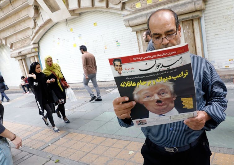 An Iranian man reads a copy of the daily newspaper 'Omid Javan' with a picture of Donald Trump on the cover.