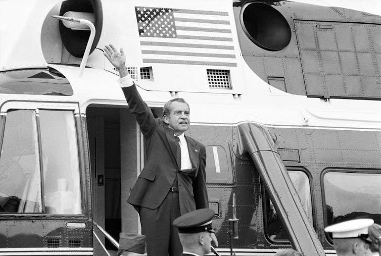 A man waves from the steps of a helicopter.