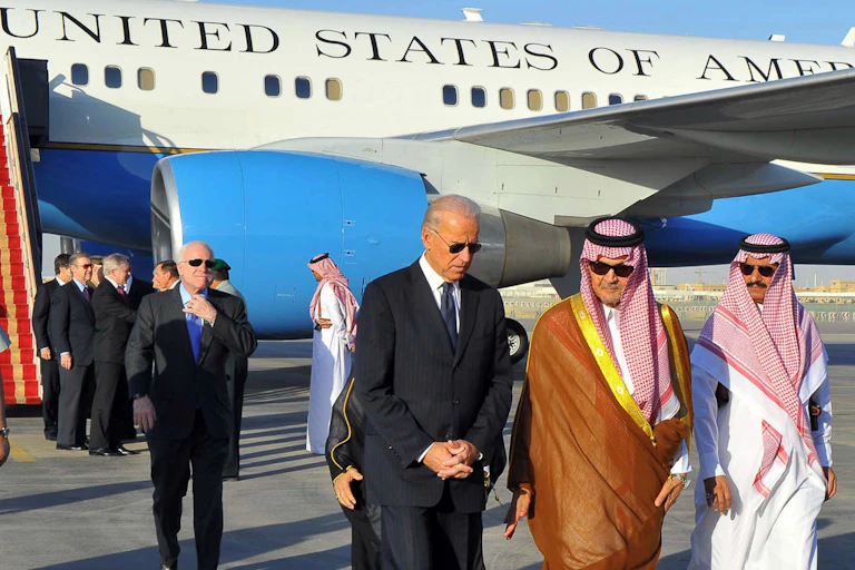 Biden walks with two Saudi men at an airport, with Air Force Two visible in the background