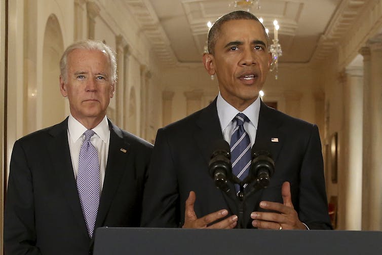 Obama speaks at a lectern with Biden behind his right shoulder
