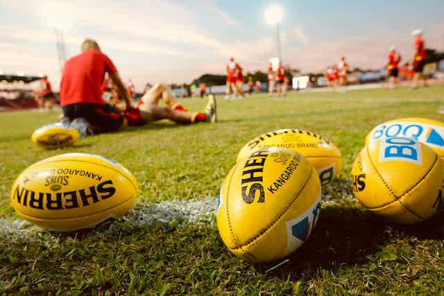 Footballs and AFL players at a training session