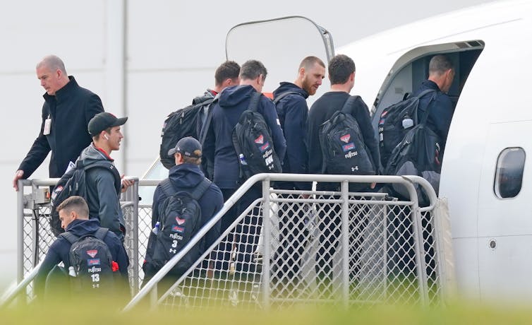 AFL players board a plane
