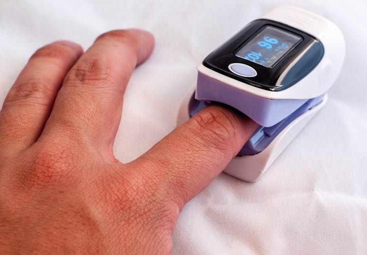 A person with a pulse oximeter on their finger, measuring their blood oxygen levels