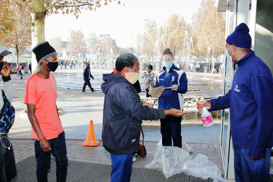 People wearing masks and getting their hands sanitised.