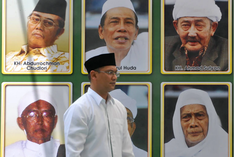 A man walks in front of pictures of Muslim leaders in East Java, Indonesia.