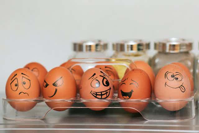 A box of eggs with emotional faces drawn on.