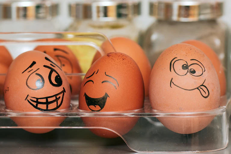 A box of eggs with emotional faces drawn on.