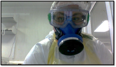A researcher wears googles, a respirator and protective clothing inside a laboratory.