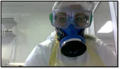 A researcher wears googles, a respirator and protective clothing inside a laboratory.