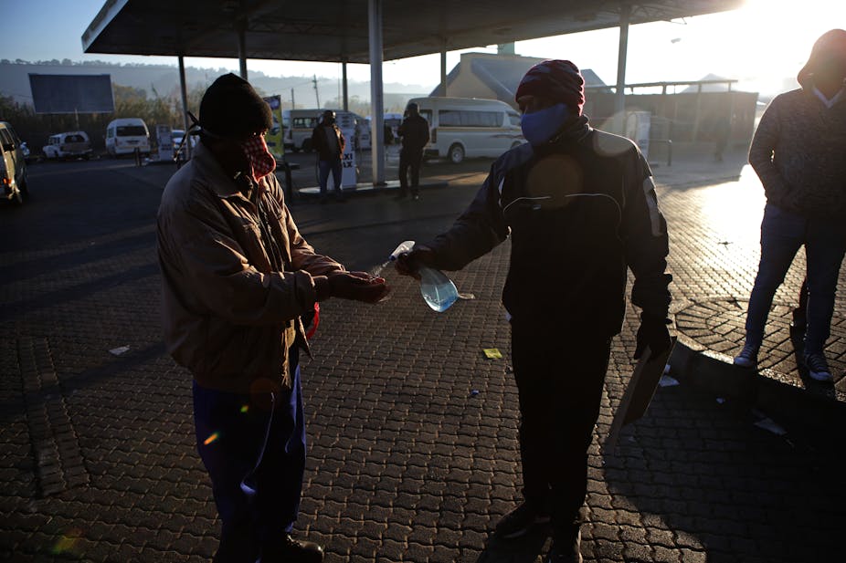 A man gets his hands sprayed with sanitiser at a taxi rank