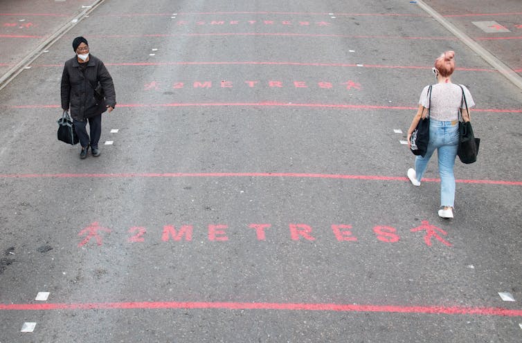 Two women walk down a road with