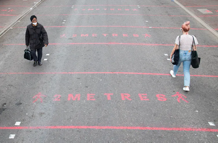 Two women walk down a road with