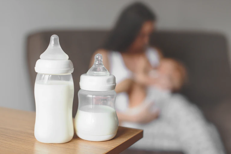 A woman and her baby in the background with two bottles in the foreground.