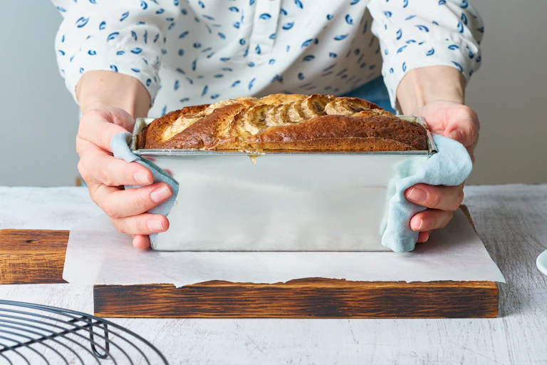 Baking tin of banana bread in woman's arms.