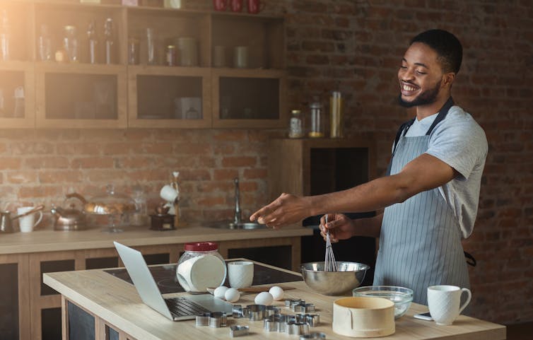 Man making cake points at open laptop.