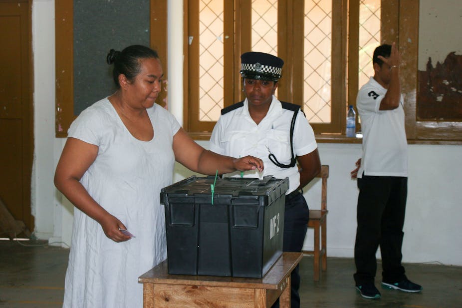 A young woman in a white dress casts her ballot at a polling station in Seychelles during the country's 2016 general election