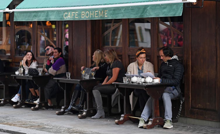 People drinking at tables outside a bar