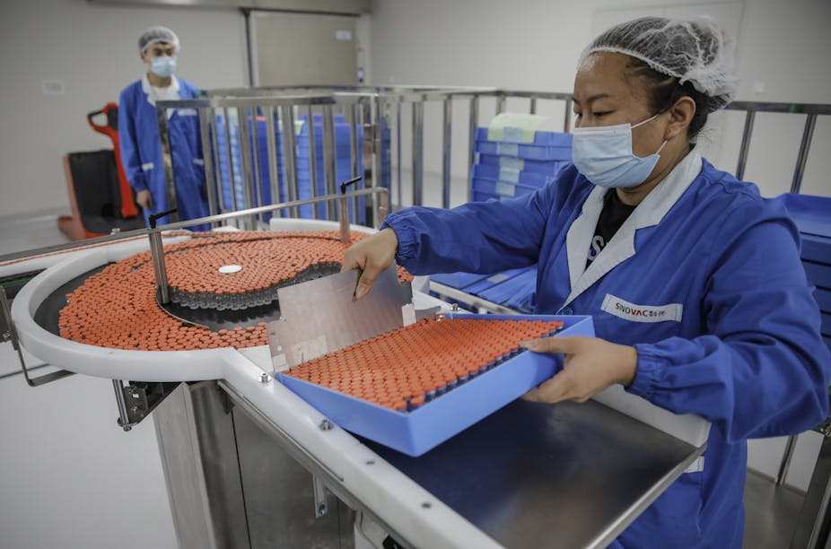 Woman holds tray of vaccines in factory.