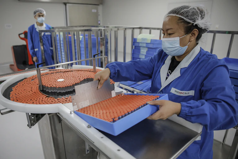 Woman holds tray of vaccines in factory.