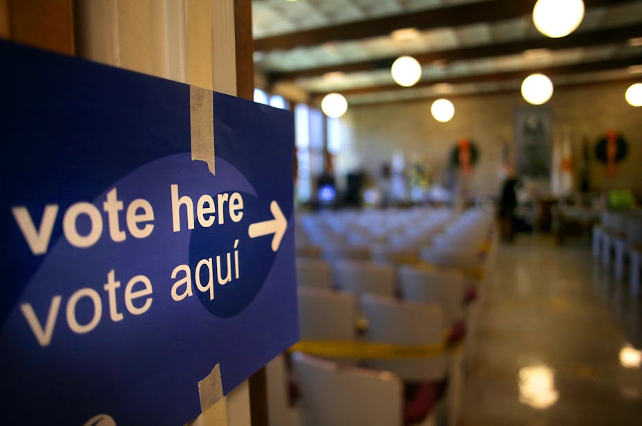 A blue sign reading 'vote here'/'vote aqua' directs voters to an indoor polling place