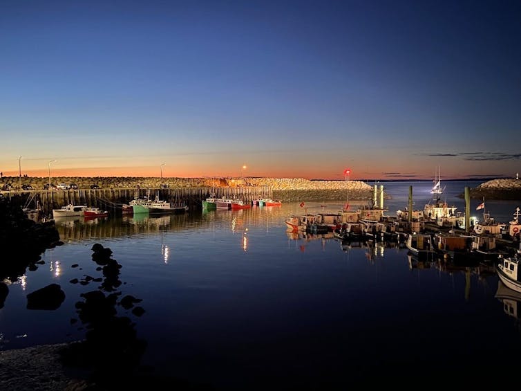 The sun sets over a harbour.